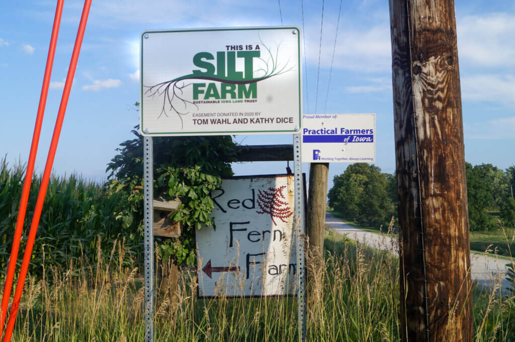 Sustainable Iowa Land Trust Sign (SILT) sign in green and white marking Red Fern Farm as a conservation easement donated by Tom Wahl and Kathy Dice in 2020.